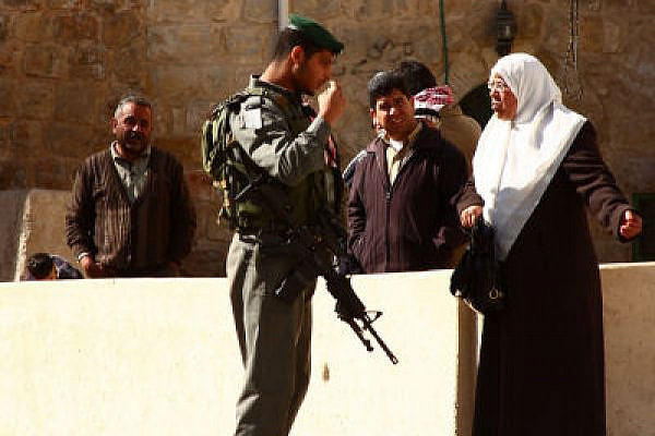 Israeli border policeman faces a Palestinian woman in Hebron (Photo: Yossi Gurvitz)