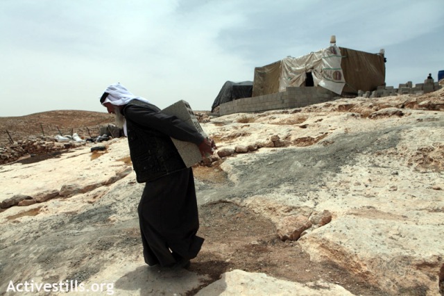 Man carrying bricks for a new house in Mufagarah (Anne Paq / Activestills)