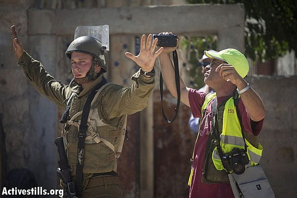 An Israeli soldier prevents a Palestinian cameraman to document the house to house search conducted by the Israeli army in the center of the village during the weekly protest against the occupation and settlements in the West Bank village of Nabi Saleh, August 24, 2012. (photo: Oren Ziv/Activestills.org)