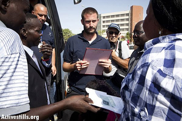 A representative of the Authority of Population and Immigration checks South Sudanese people boarding a bus for Ben-Gurion airport. The refugees were gathered in a raid conducted by Oz Unit. Arad, Israel, June 17, 2012. (Photo: Yotam Ronen/Activestills.org)