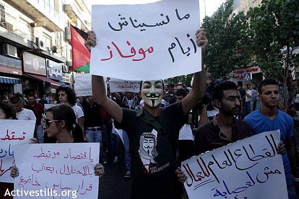 A mask protester wears a sign reading " we did not forget the Mofaz daysl " (referring to earlier protest against a planned visit of Israeli Vice Prime Minister Shaul Mofaz) during a protest marching to the Muquata, the PA headquarters; in the West bank city of Ramallah to protest the rising cost of living, especially fuel and food, and calling for the resignation of the Palestinian National Authority's Salam Fayyad and the end of the Paris protocol, September 11, 2012. Protesters condemned continuous increases in taxes, cuts to public sector wages and the oppressive rule of the Paris Protocol on Economic Relations, an agreement signed with Israel in 1994, which laid out the economic relations between Israel and the PA within the Oslo framework, and which turned out to be mostly about ensuring Israel's economic domination of the Palestinian market and has prevented the development of an independent Palestinian economy. Some protesters also called for the end of the Oslo accords.
 (photo: Anne Paq/Activestills.org)