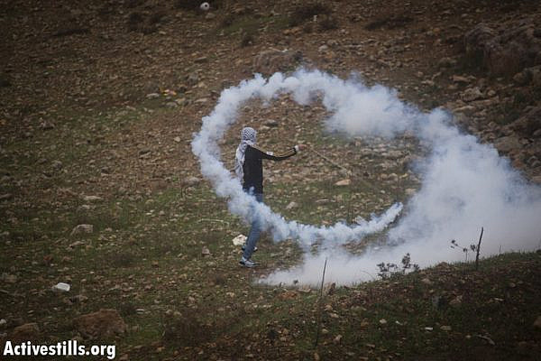 A Palestinian youth uses his sling shot to throw back a tear gas canister shot by the Israeli army during the weekly protest against the occupation in the West Bank village of Nabi Saleh, November 23, 2012. (Photo by: Oren Ziv/ Activestills.org)