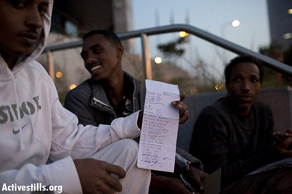 An African asylum seeker shows a list of names of some of those waiting to renew their temporary visa, outside the Israeli Ministry of Interior's offices in Tel Aviv, early morning, November 1, 2012. Asylum seekers gather from midnight outside the offices to be first in line. Only 60-70 visas are renewed each day, meaning many have to return the next day to repeat the process. Unlike Israelis coming to the offices, the asylum seekers are not allowed into the building. An officer comes out and takes the documents, leaving the applicants outside, sometimes waiting for hours. The 2A5 temporary visa must be renewed every 3 months, regardless of the amount of time a person has been living in Israel. The temporary visa is their only legal document issued by the Israeli government, and can be revoked at any time without reason. (photo by: Oren Ziv/ Activestills.org)