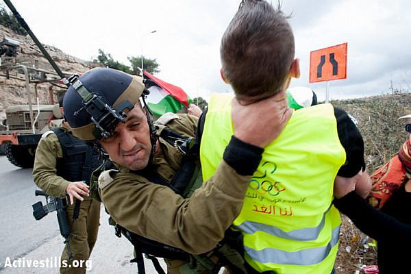 An Israeli soldier grabs an international activist by the neck while attempting to make an arrest, Al Nashash Junction, November 14, 2012. The activists intended to block traffic on Route 60, the main north-south highway in the West Bank. (photo: Ryan Rodrick Beiler/Activestills.org)