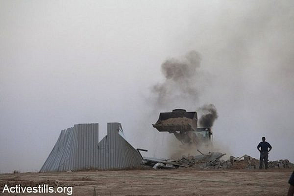 A bulldozer of the Israeli Land Administration tears down a house during the third demolition of Al-Araqib in August 2010. (Activestills.org)