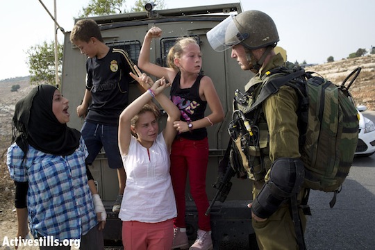 Nabi Saleh children try to prevent Wa'ed Tamimi, inside the vehicle, from being taken away. The blonde girl with the ponytail is his sister (credit: ActiveStills)