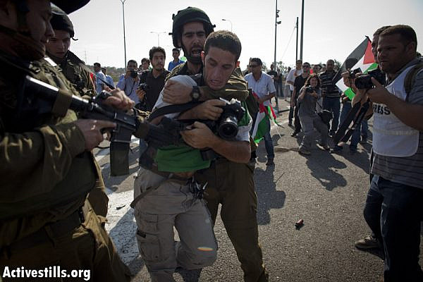 Israeli soldiers try to arrest Activestills photographer Yotam Ronen, as Palestinian and international activists block 443 highway, which connects Tel Aviv and Jerusalem through the West Bank, during a protest against the violence of  the Israeli settlers, October 16, 2012.