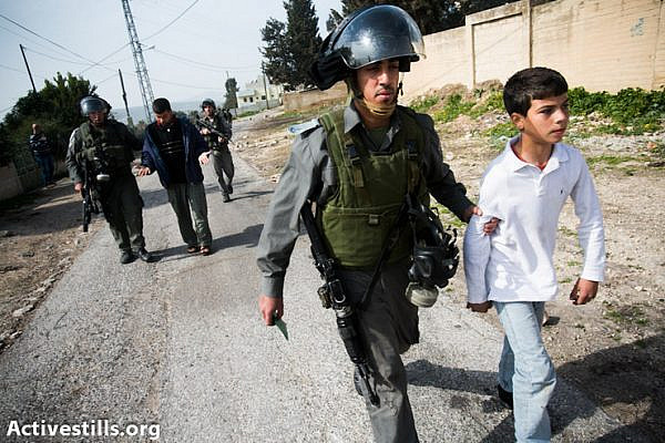 Israeli soldiers arrest a child during the weekly demonstration in Kfer Qaddum, a West Bank village located east of Qalqiliya, on January 25, 2013. There have been regular demonstrations in Kfer Qaddum since July, 2011,  protesting  the blocking of the main road east of the village which used to link it to Nablus. The child was later released. (Photo by: Yotam Ronen/Activestills.org)
