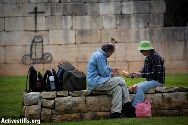 Israeli couple picnics near offensive graffiti in Bir'em (Oren Ziv / Activestills)