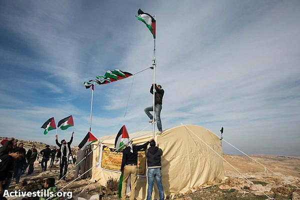 Activists raise the Palestinian flag over the Bab AlShams, reclaiming a Palestinian privately owned hilltop in the E1 area of the West Bank, currently slated for settlement by Israeli authorities.