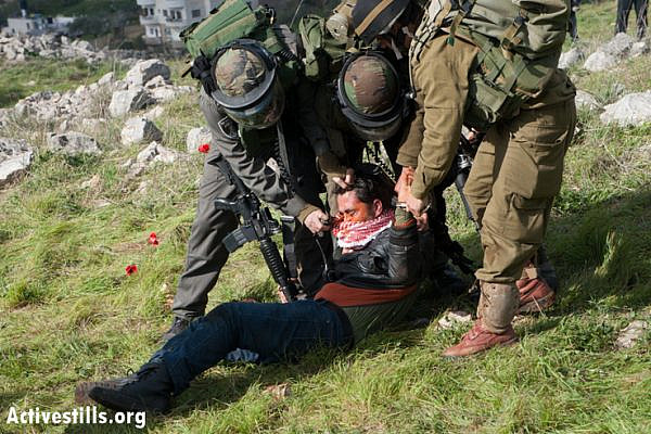 An Israeli soldier pepper sprays a restrained Palestinian activist at point blank range in a newly created protest village named Al Manatir on land belonging to the West Bank village of Burin, February 2, 2013. (Photo by: Ryan Rodrick Beiler/Activestills.org)