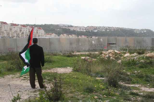 Demonstrator overlooking wall and settlement in Bil'in (Haggai Matar)