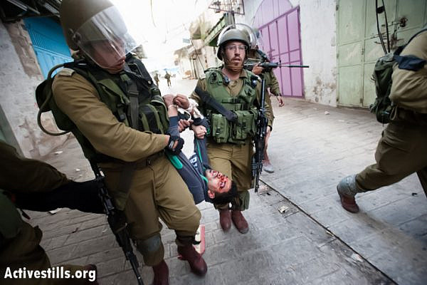 Israeli soldiers arrest a Palestinian youth, who shows signs of being beaten, following a demonstration against the occupation and in support of Palestinian prisoners the West Bank city of Hebron, March 1, 2013. (Photo by: Ryan Rodrick Beiler/Activestills.org)