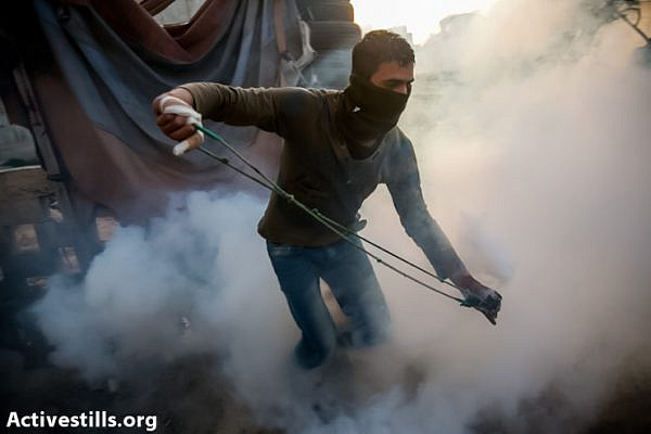 A youth throwing back a gas canister shot by israeli soilders in the West Bank village of  Nil'in on March 1, 2013, during a demonstration against the occupation. (Photo by: Yotam Ronen/Activestills.org)