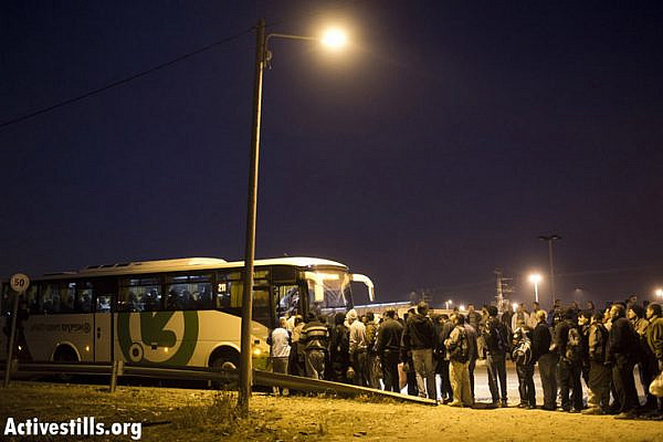 Palestinian workers wait in line to board an Israeli bus line meant for Palestinians only after crossing the Eyal checkpoint from the West Bank into Israel proper. (Photo by Activestills.org)