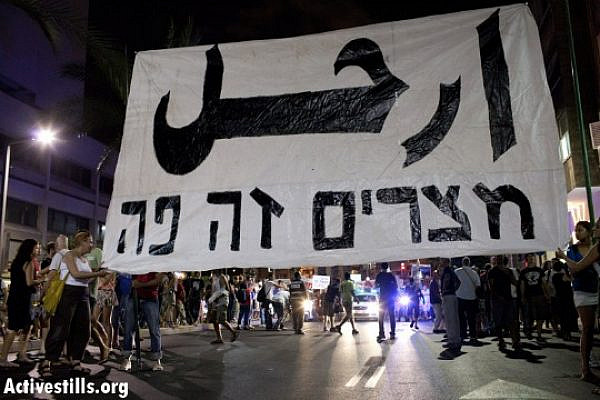 Israeli social protest activists in the summer of 2011 hold a banner emblazoned with the Arabic word "erhal" - leave. Below, the line in Hebrew reads, "Egypt is here." (credit: Oren Ziv/Activestills)