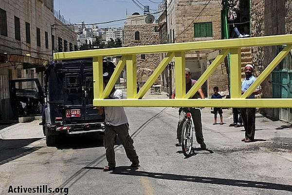 Jewish settlers close a gate blocking access to Shuhada Street in Hebron (Anne Paq/Activestills.org)