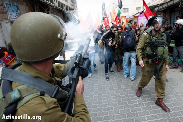 An Israeli soldier shoots tear gas into a crowd of Palestinian protesters in Hebron. March 31, 2013 (Ryan Rodrick Beiler/Activestills.org)