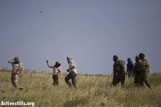 Settlers throw stones at Palestinians as IDF soldiers stand by in the West Bank village of Asira al Qibliya. April 30, 2013 (Oren Ziv/Activestills.org)