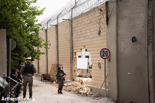 Israeli border police guard the Separation Wall between the East Jerusalem neighborhood of Ras Al 'Amud and the West Bank town of Abu Dis, May 19, 2013, after Palestinian protesters broke a large hole through it during a demonstration two days previous. (Photo by: Ryan Rodrick Beiler/Activestills.org)
