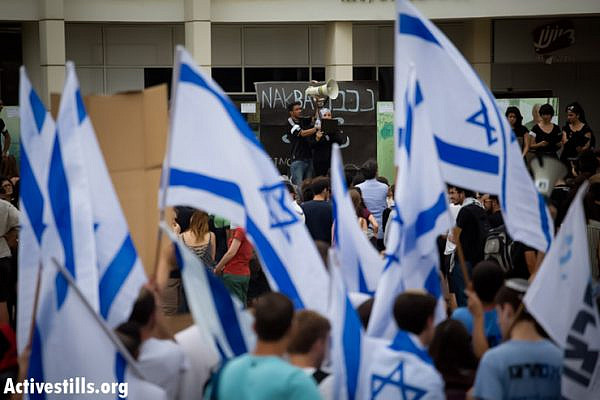 Right-wing protesters wave Israeli flags as they demonstrate against a ceremony commemorating the Nakba that was held by Palestinian and Israeli students in the entrance to the Tel Aviv University. The event took place under heavy police presence, May 13, 2013. (Photo by: Oren Ziv/Activestills.org)