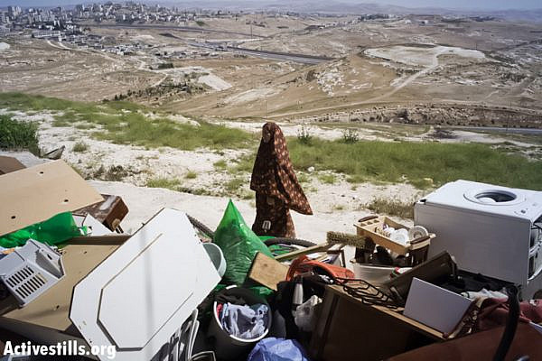 A member of the Palestinian Ghaith family stands with the belongings of her family after her house was demolished by Jerusalem municipality workers in the East Jerusalem neighborhood of At-Tur on April 29, 2013. (Tali Mayer/ Activestills.org)