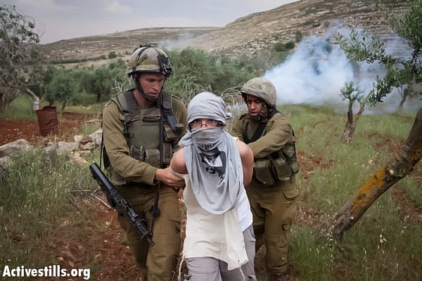 Israeli soldiers arrest an Israeli settler after he threw stones at Palestinian demonstrators from the West Bank villages of Deir Jarir and Silwad during a  protest against construction on their land by members of the nearby Jewish settlement of Ofra on May 3, 2013. Israeli setters marched into the lands of Silwad and deir Jarir, attacking Palestinian protesters as the Israeli army looked on.
After two hours of clashes, border policemen arrested just the one settler and let all the others escape. (hoto: Oren Ziv/ Activestills.org)