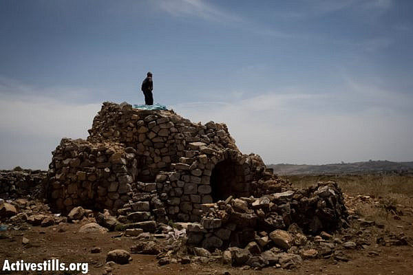 A Palestinian man stands on top of a stone structure, used by Palestinian farmers of the area, which Israeli settlers took over a few weeks ago, in the West Bank village of Deir Jarir, May 23, 2013. (Photo by: Oren Ziv/ Activestills.org)