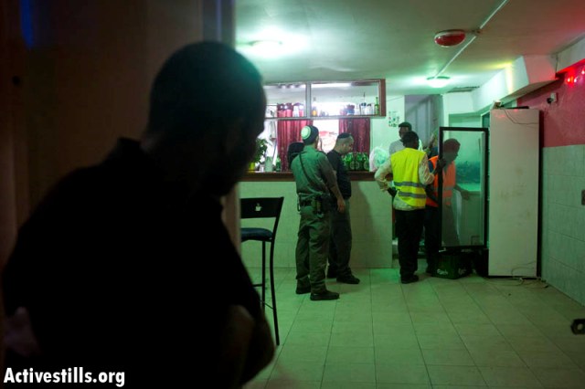 Officials and movers take fridge out of asylum seeker's resturant (Oren ziv / Activestills)