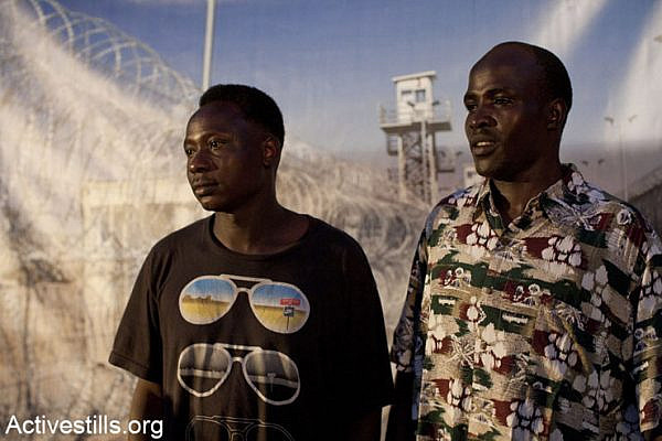 Refugees pose infront of a poster of Saharonim prison, during the Refugee Day in tel Aviv on June 20, 2013.
(Keren Manor/Activestills.org)
