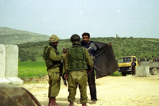 Israeli soldiers search a Palestinian at an IDF checkpoint. (photo: Breaking the Silence)