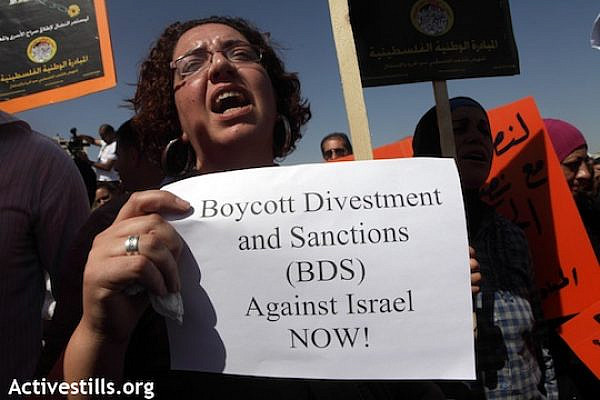 A woman carries a sign in support of the Boycott, Divestment and Sanctions (BDS) campaign, October 11, 2011 (Anne Paq/Activestills.org)