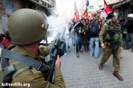 An Israeli soldier fires tear gas toward Palestinian, Israeli, and international activists during a demonstration against the occupation and in support of Palestinian prisoners the West Bank city of Hebron, March 1, 2013. (Photo by: Ryan Rodrick Beiler/Activestills.org)
