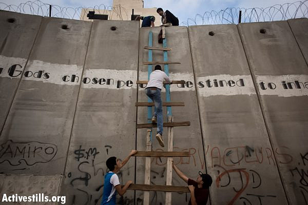 Palestinians use a ladder to climb over the Israeli wall in A-Ram, north of Jerusalem, on their way to Al-Aqsa mosque, in the Old city of Jerusalem to attend the second Friday prayer in the fasting month of Ramadan, 19 July 2013. (Photo by: Oren Ziv/ Activestills.org)