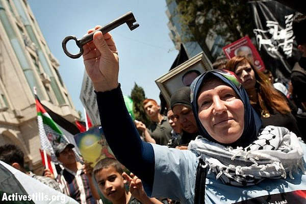 A Palestinian woman carries a key, a symbol of the Nakba and the right of return, May 15, 2012, Ramallah. (Ryan Rodrick Beiler/Activestills.org)