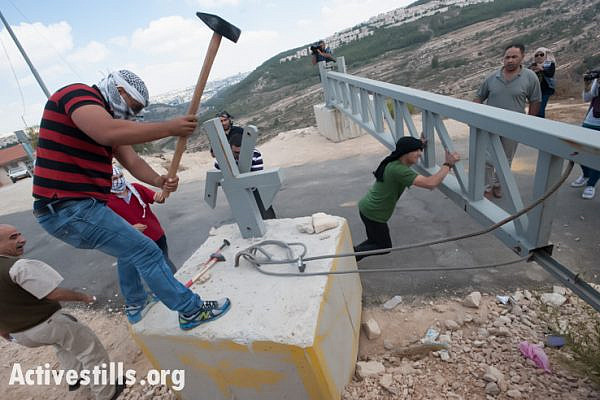 Palestinian and International activists remove a gate built by the Israeli army blocking the road between the village of Al Walaja and the West Bank town of Beit Jala, October 3, 2013. (photo: Ryan Rodrick Beiler/Activestills.org)