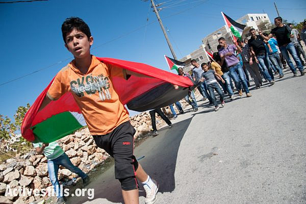 Palestinians, accompanied by international and Israeli solidarity activists, march to commemorate seven years of popular resistance in the West Bank village of Al Ma'sara, October 25, 2013. The weekly demonstration protests the construction of the Israeli separation wall on village land, which would cut off access to agricultural areas. (Photo: Ryan Rodrick Beiler/Activestills.org)
