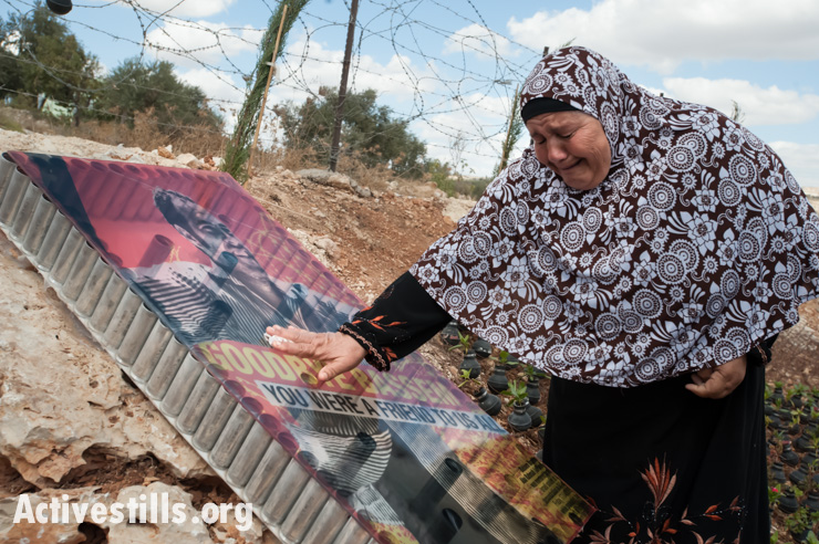 Before a weekly demonstration against the wall, Sabiha Abu Rahmah weeps at the memorial garden planted on the spot where her son, Bassem, in a 2009 protest, was shot and killed with a high-velocity tear gas grenade fired by Israeli soldiers, Bil'in, West Bank, October 4, 2013. 