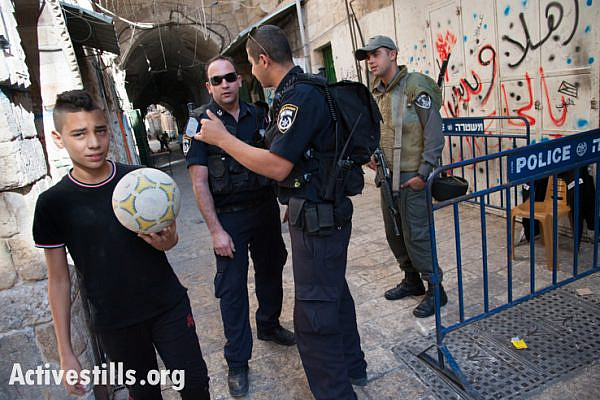 A Palestinian boy passes an Israeli checkpoint in the Old City of Jerusalem, October 12, 2013. Illegally annexed by Israel in 1967, the international community considers East Jerusalem, including the Old City, to be occupied Palestinian territory. (photo: Ryan Rodrick Beiler/Activestills.org)