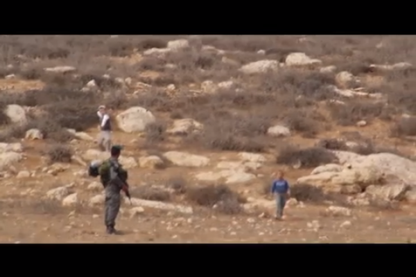 A Border Policeman looks on as a six-year-old Palestinian and a settler child share a moving moment. Almost. (screenshot: YouTube)