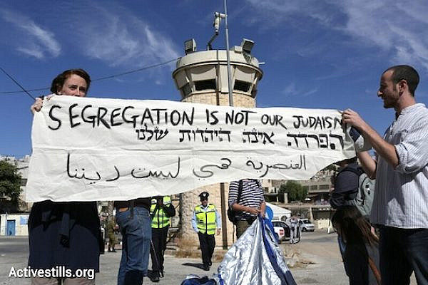 Activists hold a sign reading 'Segregation is not our Judaism,in Hebron , October 25, 2013. (Oren Ziv/Activestills.org)