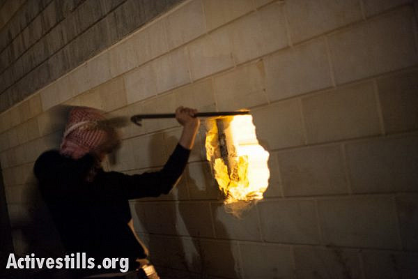 Palestinian activists break a hole in the Israeli separation wall dividing land belonging to the West Bank town of Al Khader in the late night hours of November 22, 2013. (photo: Activestills)