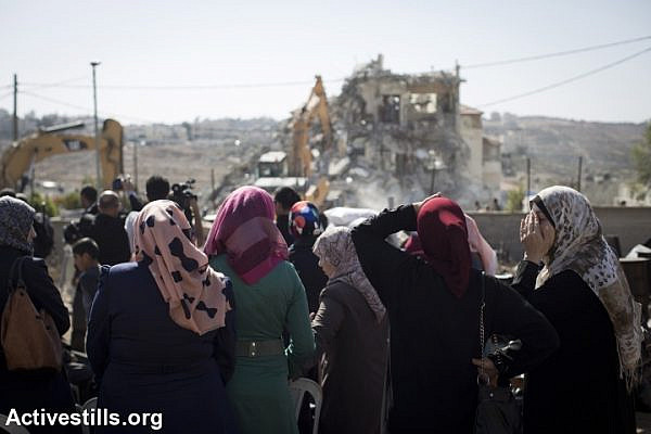 Palestinian women look on and react as Jerusalem municipality workers demolish a residential building in an East Jerusalem neighborhood of Beit Hanina, on October 29, 2013. (Oren Ziv/Activestills.org)