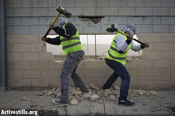 Palestinians use hammers to break through the separation wall in the West Bank village of Bir Nabala. (photo: Activestills)