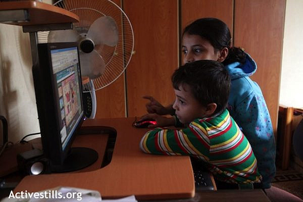 Palestinian children in Gaza use a computer. (Illustrative photo: Anne Paq/Activestills.org)