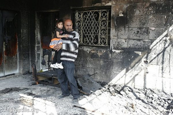 Khaled Abed a-Rahman Dar Khalil surveys the damage to his home while holding his daughter. Seven members of the Khalil family were inside their home when it was firebombed by Israeli extremists early Thursday morning. (Photo: Oren Ziv/Activestills.org_