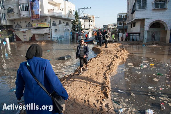 Palestinians pass along a sand walkway connecting flooded areas of the Al Nafaq neighborhood of Gaza City. (photo: Ryan Rodrick Beiler/Activestills.org)