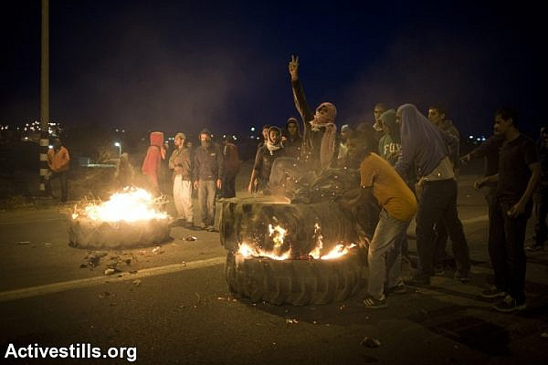 Bedouin youth set tires barricade on fire during a protest against the Israeli government's Prawer Plan, on road 31 on November 30, 2013 near the town of Hura, Israel.
