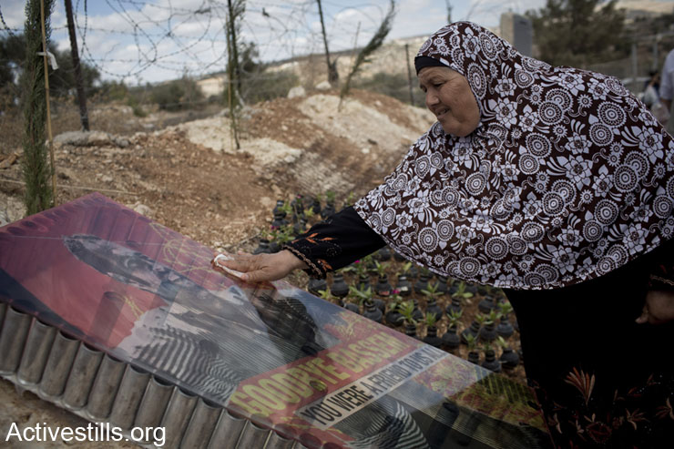 Palestinian Subhiya Abu Rahme cleans the memorial monument of her son, Bassem who was shot to death by an Israeli soldier during a protest in the village in 2009; October 4, 2013. The garden was set with many flowers put in empty gas canisters and inaugurated during the eight Bil'in popular struggle conference. 