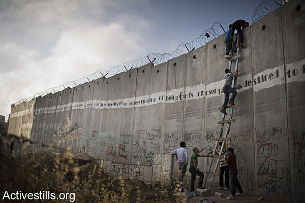 Palestinians use a ladder to climb over the Israeli wall in A-Ram, north of Jerusalem, on their way to Al-Aqsa mosque, in the Old city of Jerusalem to attend the second Friday prayer in the fasting month of Ramadan, 19 July 2013.